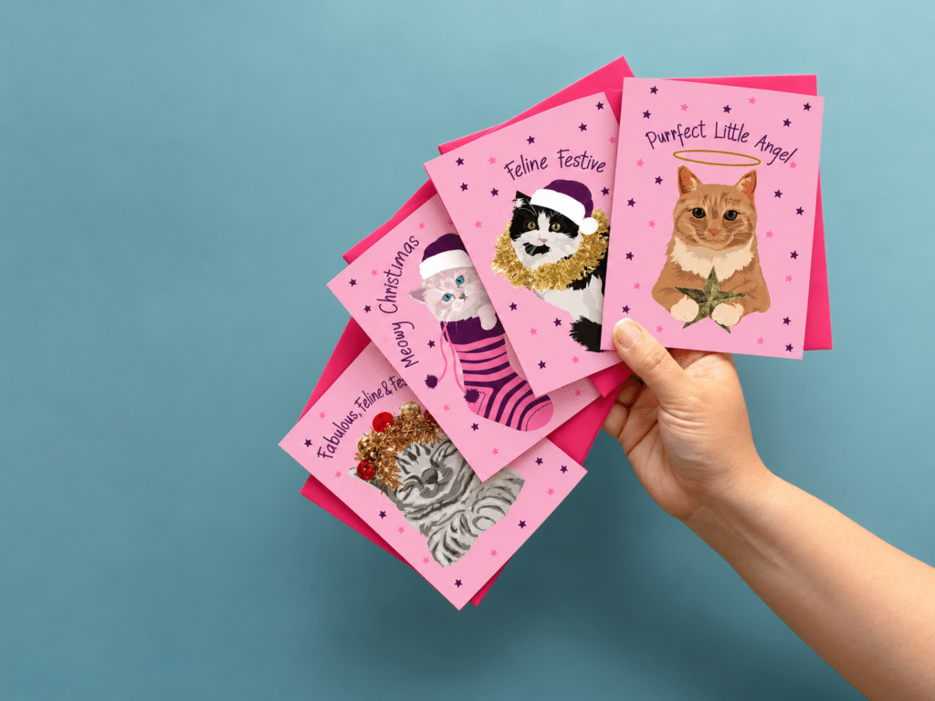 Meowy Christmas card featuring a grey kitten in a pink and purple stocking, photographed with Christmas decorations lorna syson new christmas collection