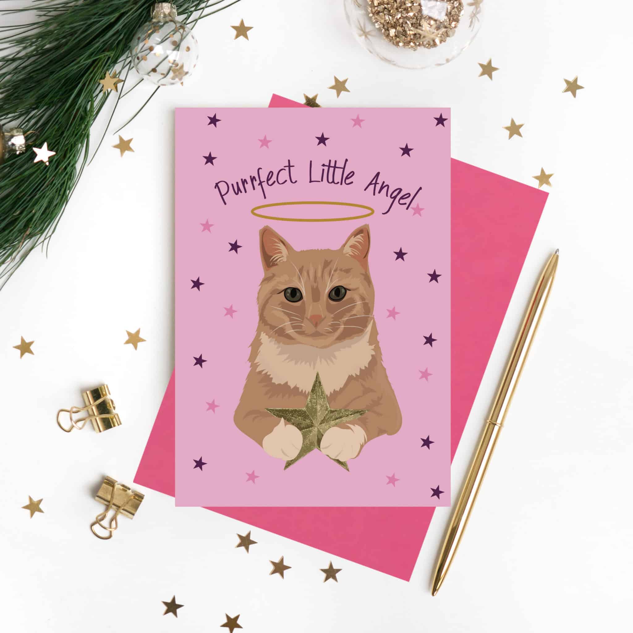 Purrfect Little Angel Christmas card featuring a ginger cat with a halo holding a star on a pink background with pink envelope by lorna syson