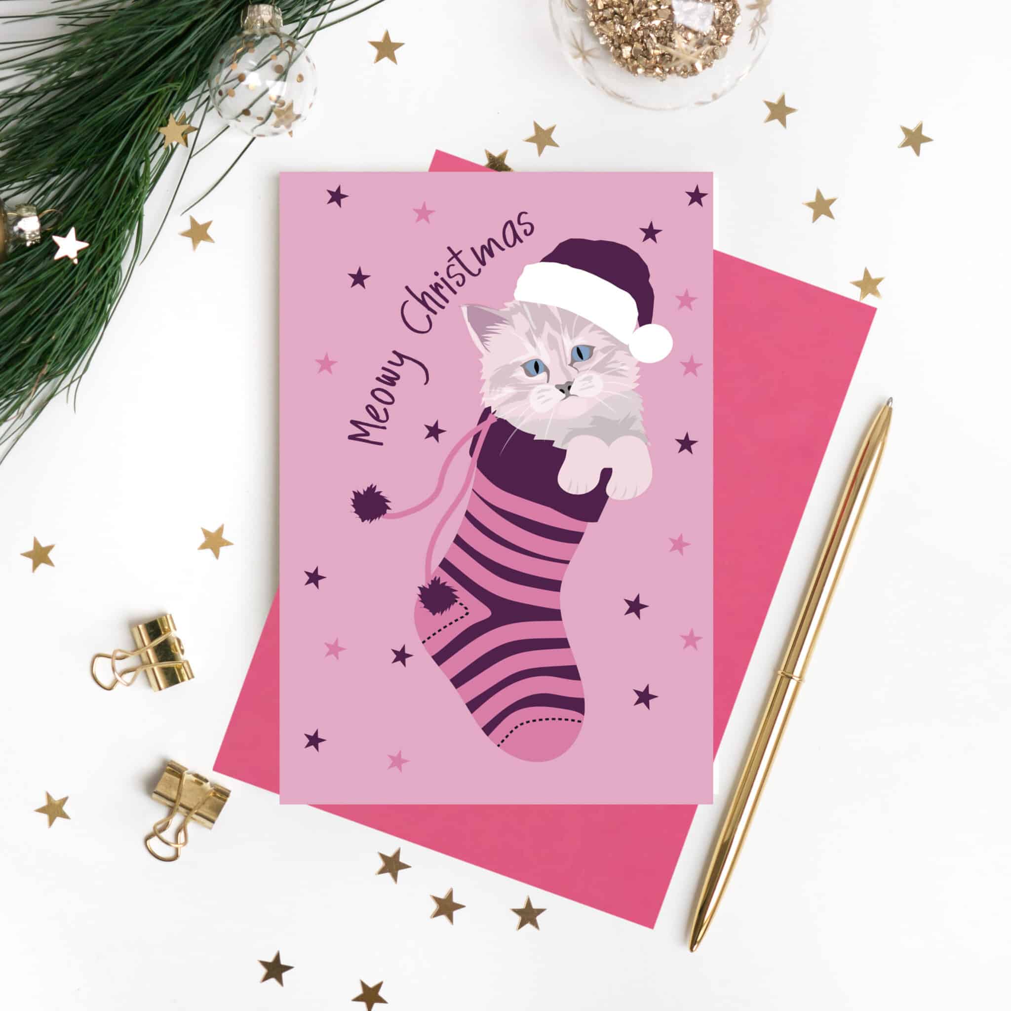 Meowy Christmas card featuring a grey kitten in a pink and purple stocking, photographed with Christmas decorations by lorna syson