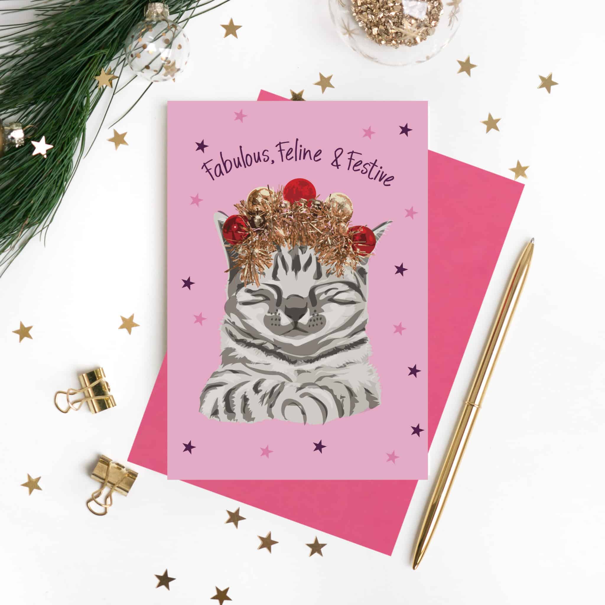 Fabulous, Feline & Festive Christmas card featuring a grey tabby wearing a tinsel and bauble crown on a pink background